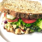 sandwich that looks like tuna but made of chickpeas. Whole grain bread, lettuce, tomatoes, pickles showing, Chickpea Tuna Salad,